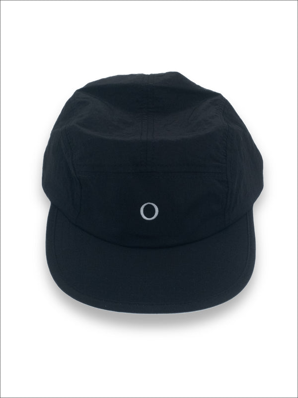 A black five-panel camp cap with a small white embroidered circle logo on the front, displayed against a clean white background.